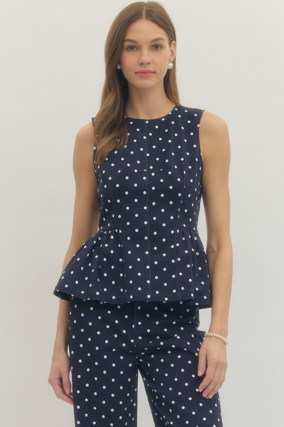 sleeveless polka dot top with a flattering peplum hem and tailored fit