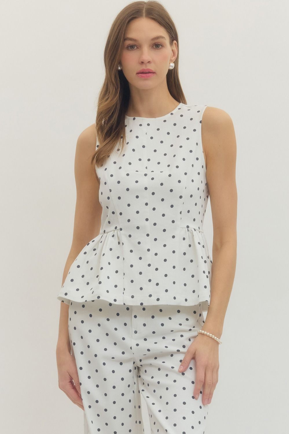 sleeveless polka dot top with a flattering peplum hem and tailored fit