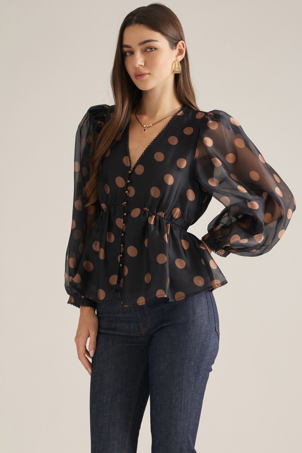 Women's polka dot woven top with V-neckline, long puff sleeves, decorative trim, button front, and elasticized back waist