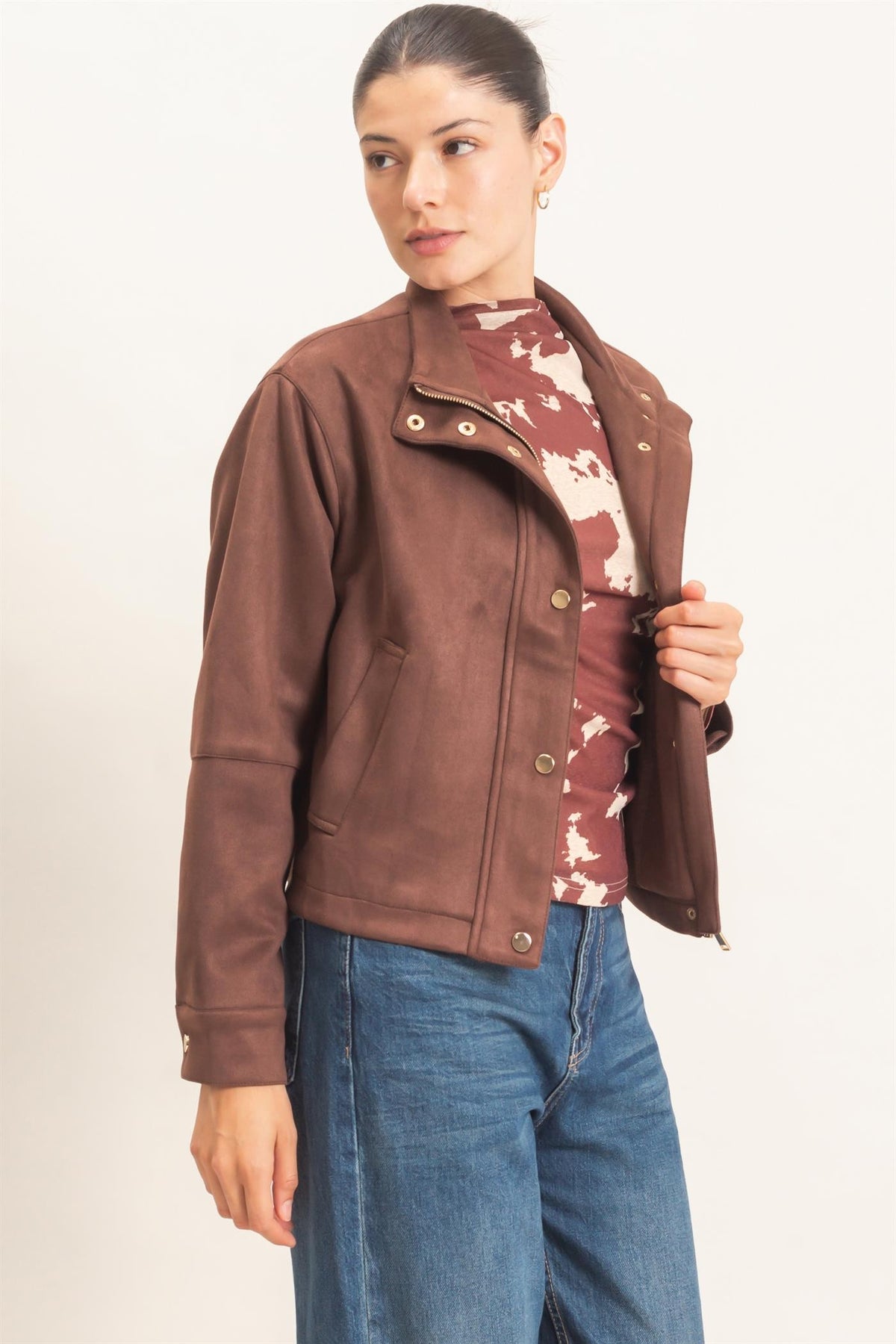 A polished faux suede jacket featuring a structured silhouette, high collar, metal snap closures, subtle stitching, and convenient side pockets.