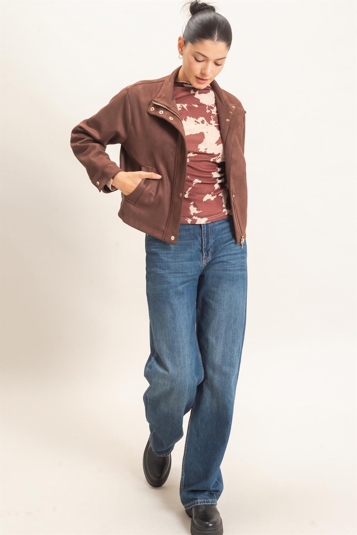 A polished faux suede jacket featuring a structured silhouette, high collar, metal snap closures, subtle stitching, and convenient side pockets.