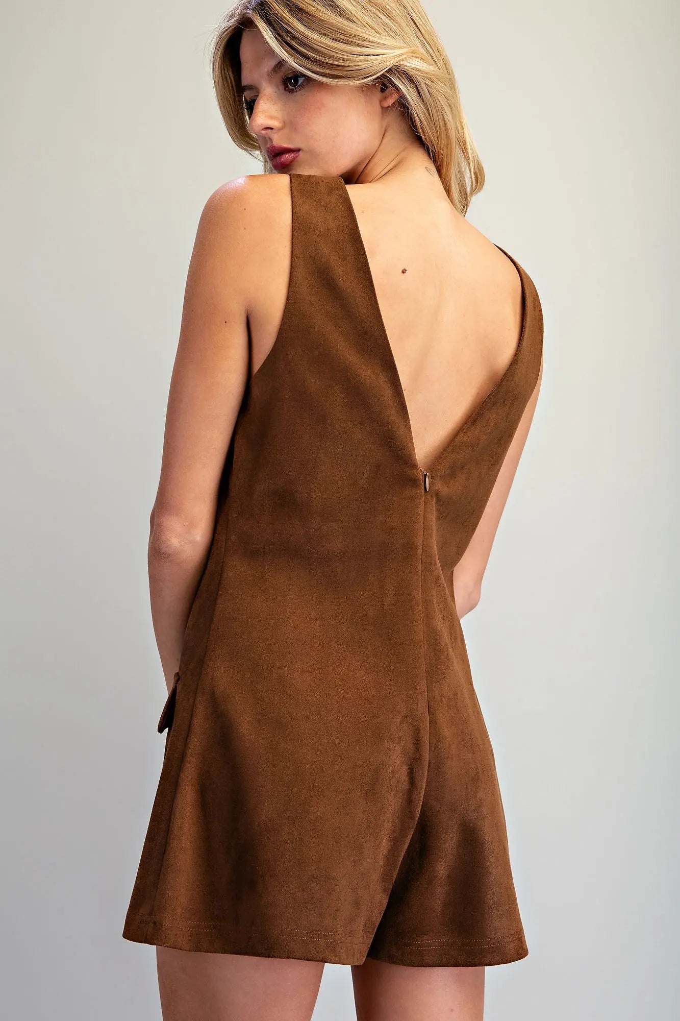 A vintage-inspired faux suede skort romper featuring a flattering V-neckline, A-line silhouette, and hidden shorts for effortless style and comfort.
