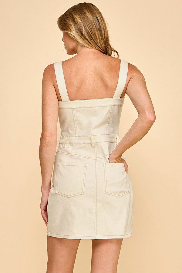 A modern cotton denim overall mini dress with adjustable straps, bold stitching, and everyday-cool appeal.