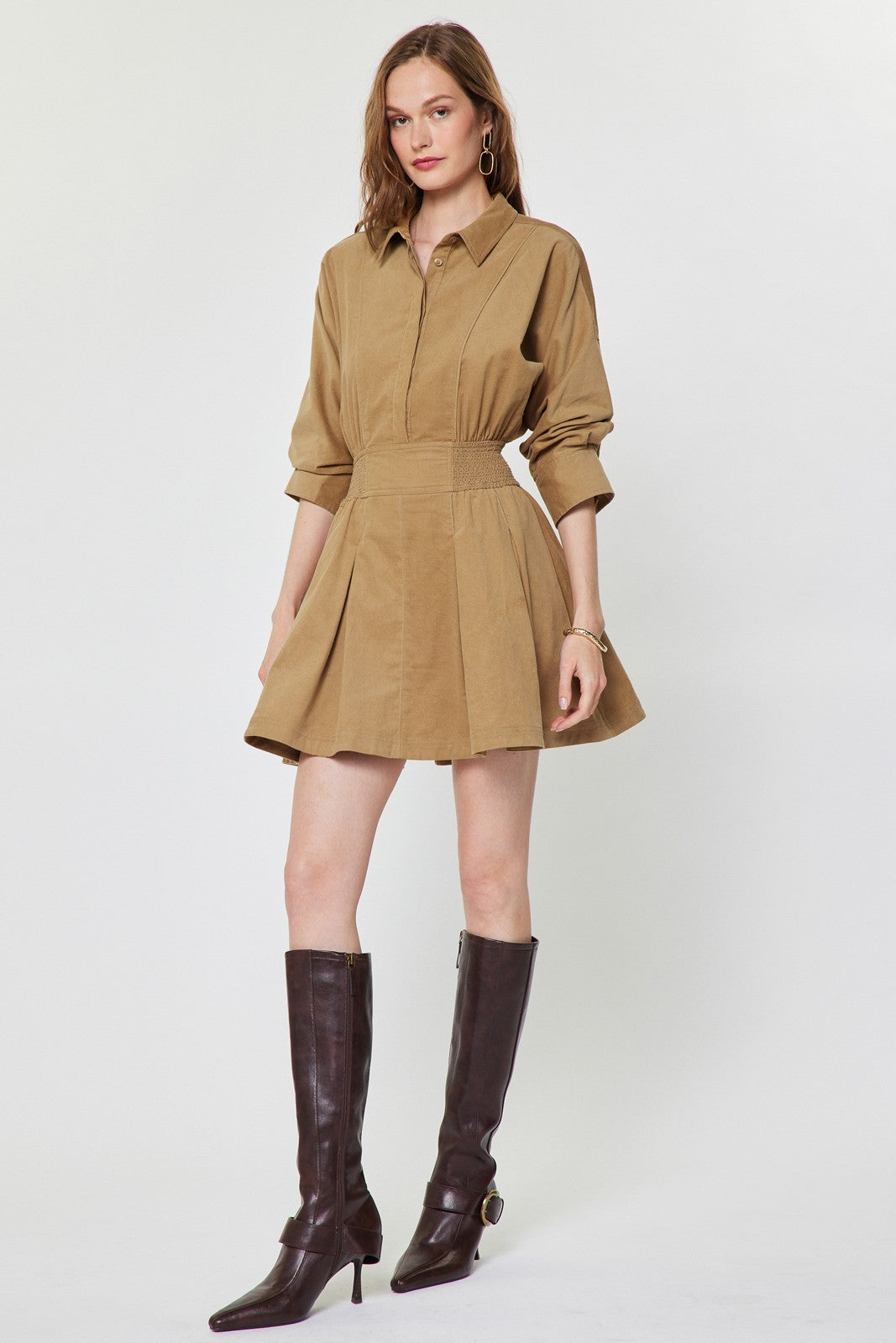 A charming cotton corduroy mini dress featuring a classic shirt collar, smocked waist, flattering A-line skirt, and practical side pockets.