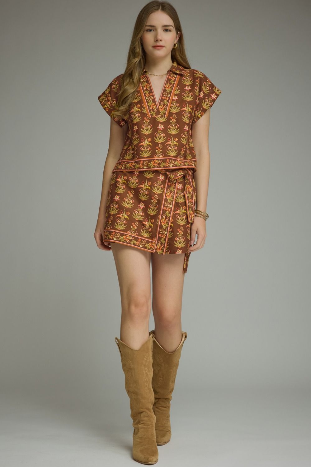 A feminine floral two-piece set featuring a flattering a contrast-trimmed V-neck top and coordinating wrap-front mini skort for an effortlessly polished boutique look.


