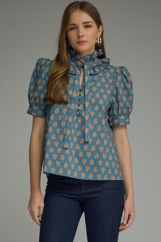  printed puff sleeve blouse features a feminine ruffle neckline, self-tie detail, and timeless button-front styling.
