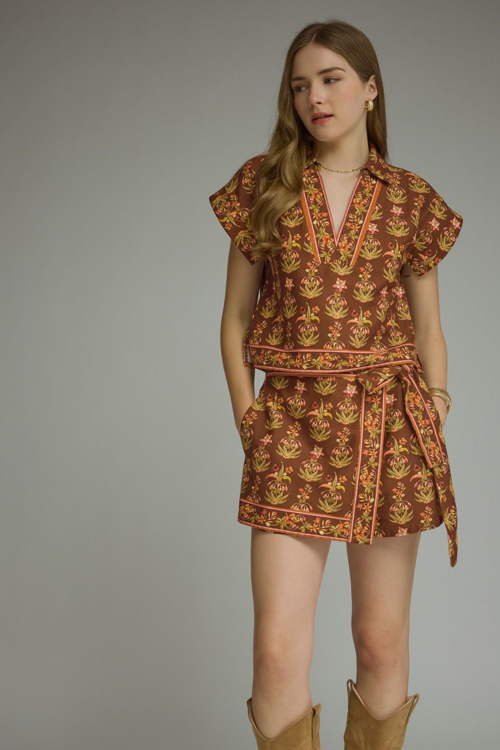 A feminine floral two-piece set featuring a flattering a contrast-trimmed V-neck top and coordinating wrap-front mini skort for an effortlessly polished boutique look.

