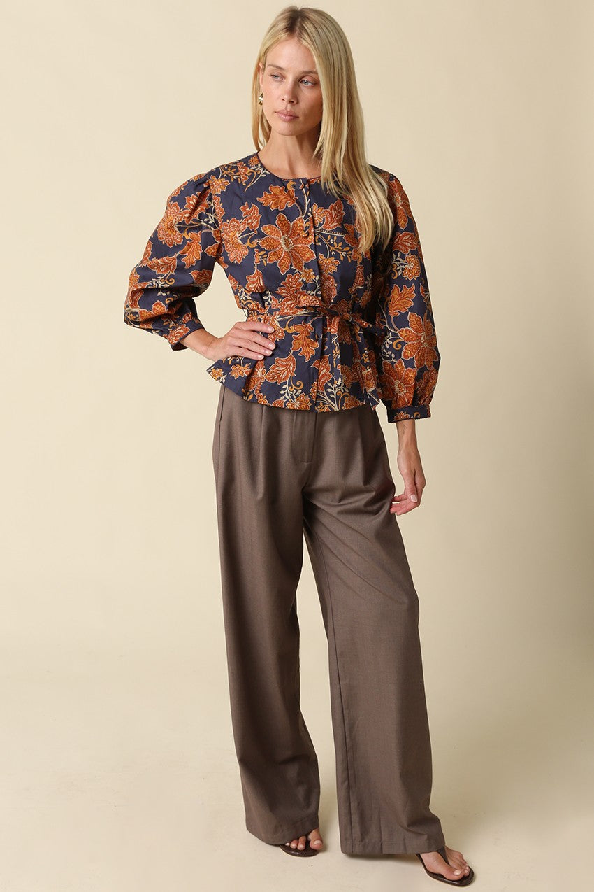 A feminine floral blouse featuring puff sleeves, a flattering peplum silhouette, and a front tie waist for an effortlessly polished look.

