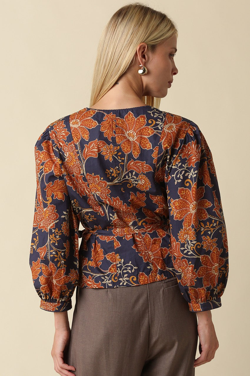 A feminine floral blouse featuring puff sleeves, a flattering peplum silhouette, and a front tie waist for an effortlessly polished look.

