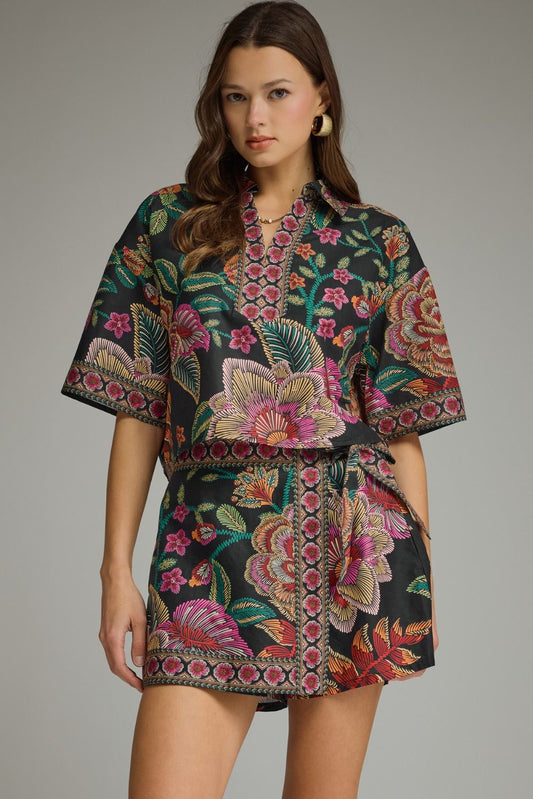 A feminine botanical print two-piece set featuring a breezy split-V top and wrap-front skort for effortless warm-weather style.