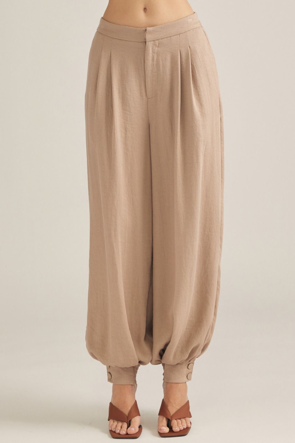 Polished woven pants featuring elegant front pleats, a comfortable elastic-back waist, and buttoned cuffs for an effortlessly tailored look.

