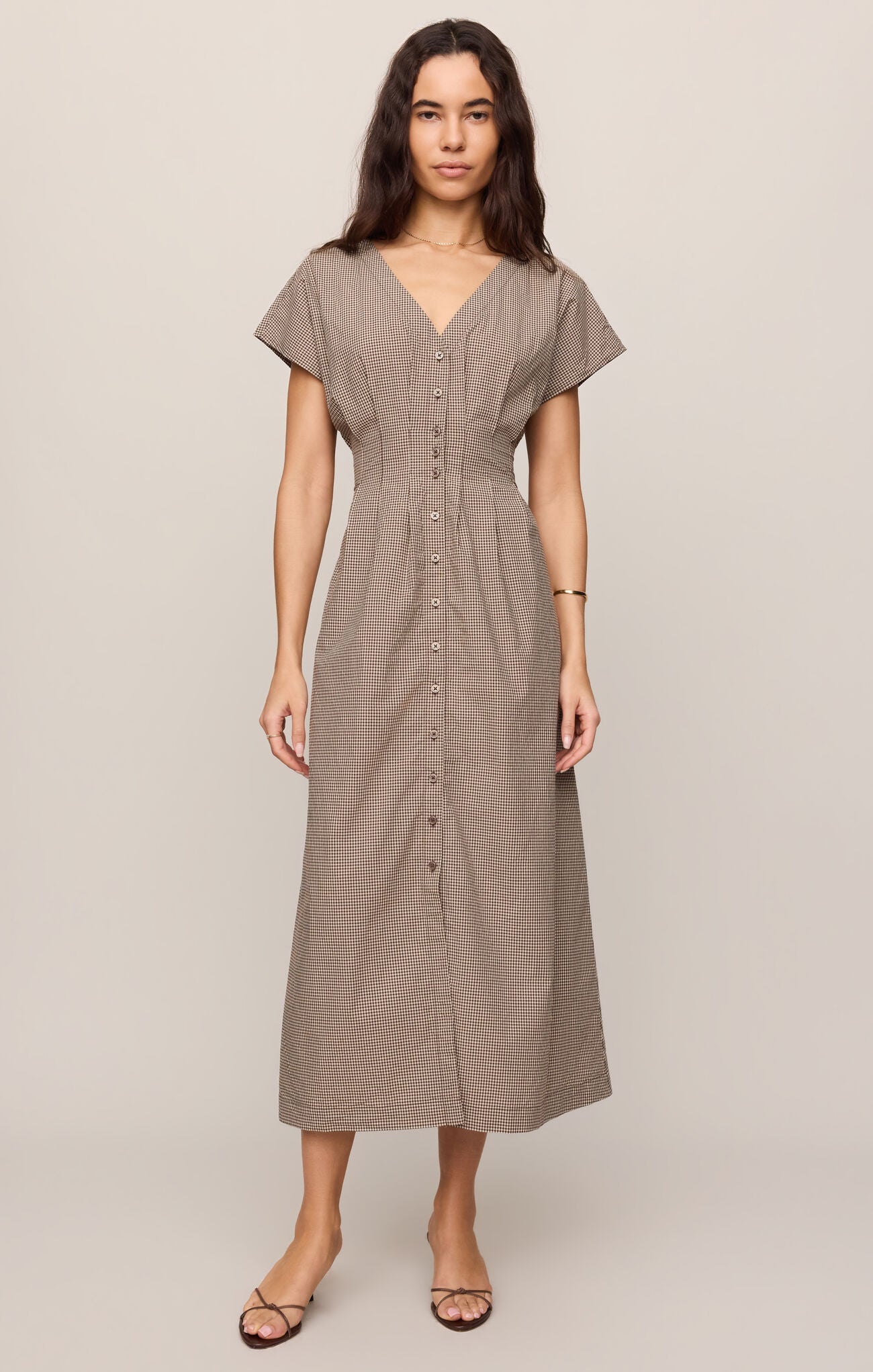 A cotton poplin shirt dress featuring a classic gingham print, flattering V-neckline, and button-front design for effortless everyday sophistication.
