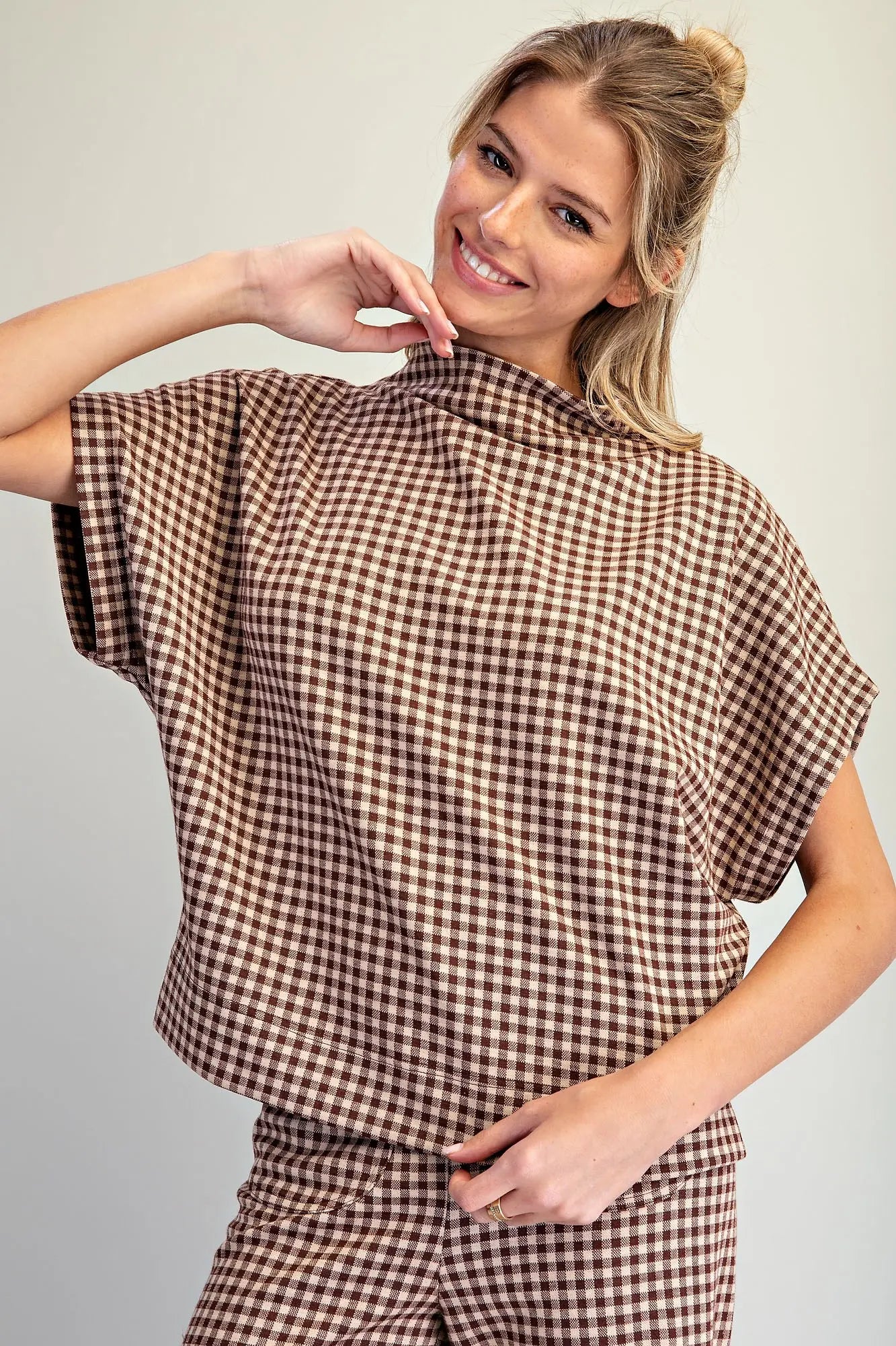 A relaxed gingham knit top featuring a modern mock neckline, wide dolman sleeves, and an effortlessly chic oversized silhouette.