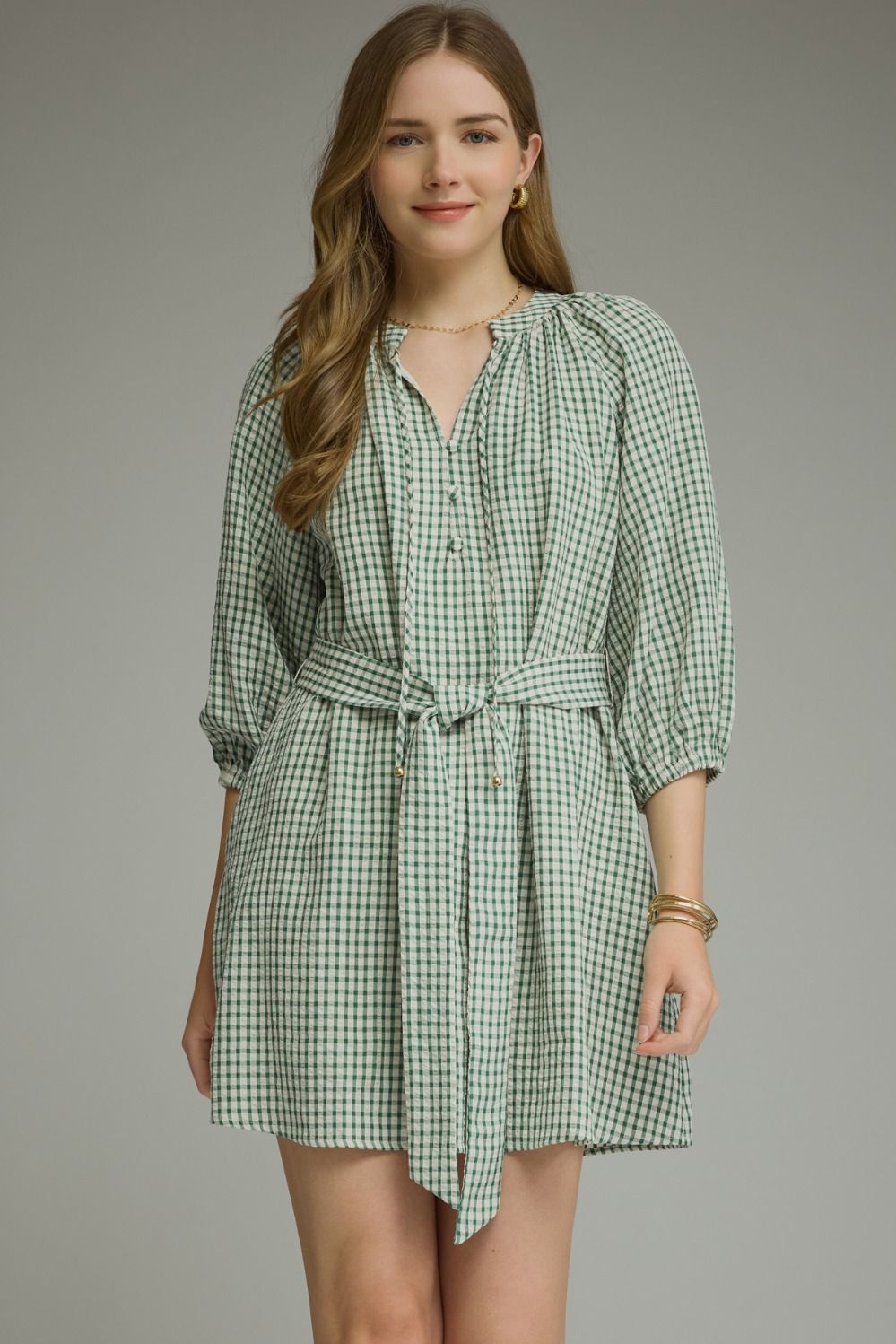 A timeless gingham mini dress featuring ¾ sleeves, a self-tie waist belt, and a button-front design for effortlessly polished style.
