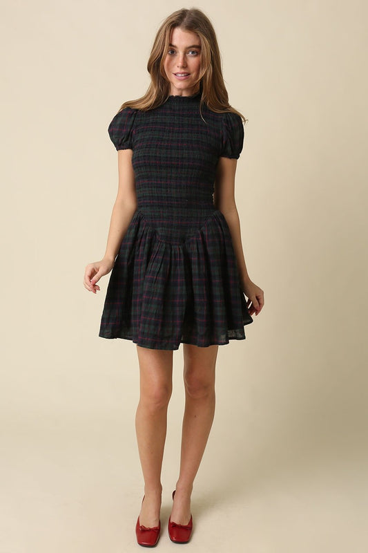 A timeless plaid mini dress featuring a flattering smocked bodice, feminine cap sleeves, and a softly gathered fit-and-flare skirt in breathable cotton.