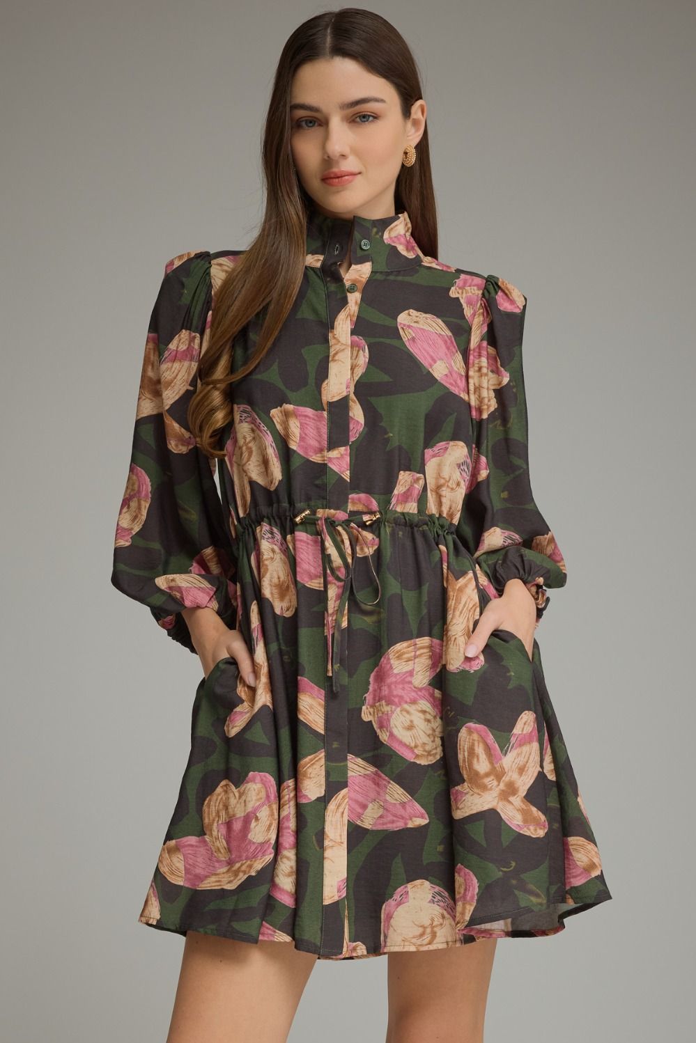 A feminine printed mini dress featuring ¾ balloon sleeves, a stand collar, adjustable drawstring waist, and convenient side pockets.

