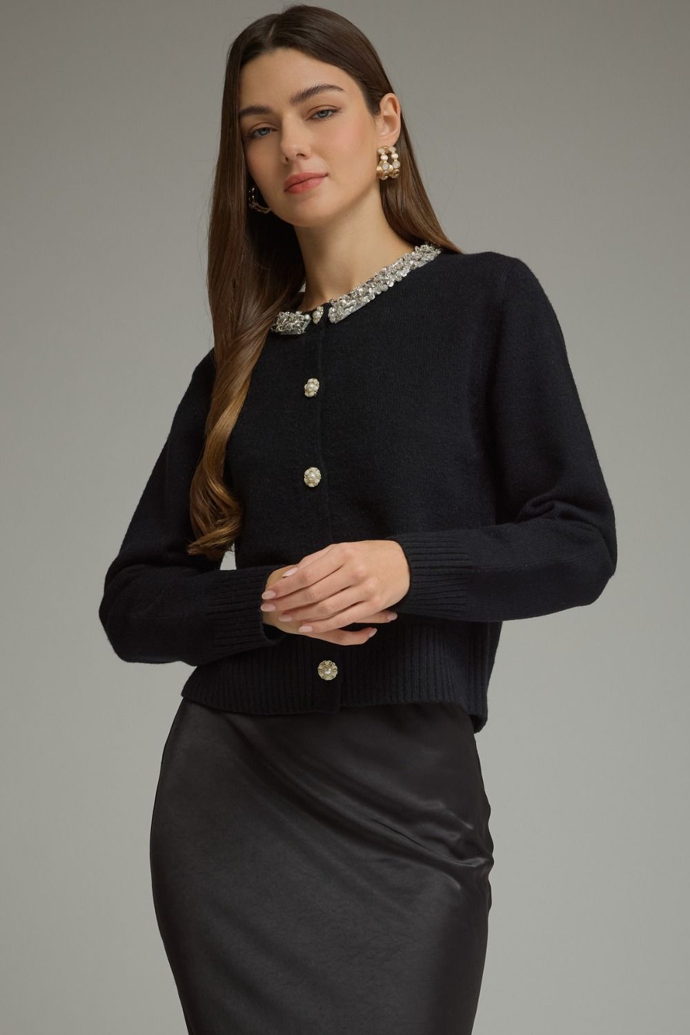 A polished knit cardigan featuring elegant rhinestone and pearl trim, pearl buttons, and classic ribbed details for a sophisticated feminine finish.