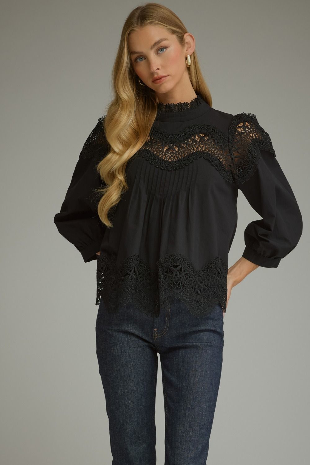 A romantic ¾ sleeve top featuring elegant pintuck detailing, delicate lace trim, and a refined mock neckline.