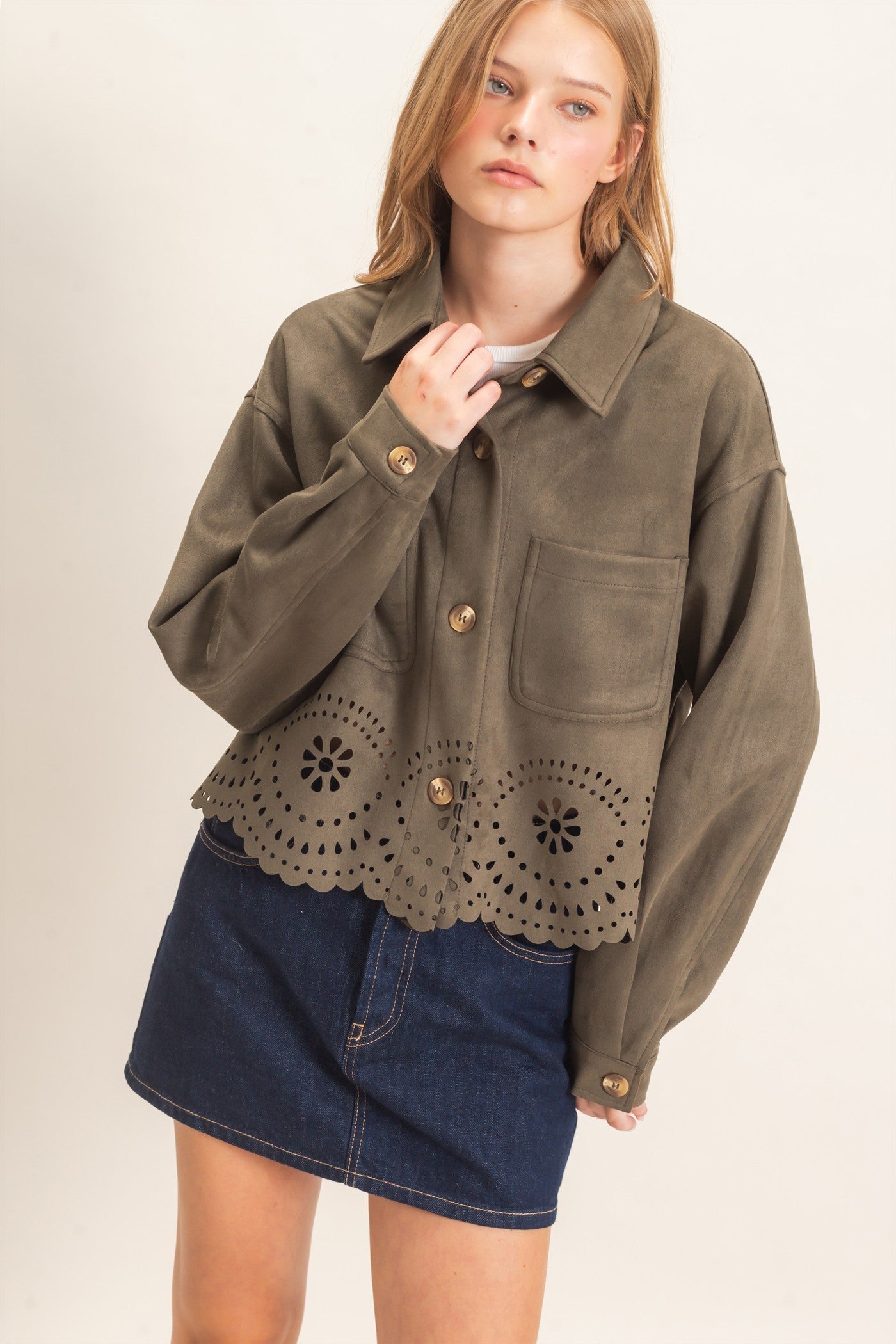 A beautifully structured suede jacket with button-front styling, chest pockets, relaxed drop shoulders, and an intricate laser-cut floral hem.