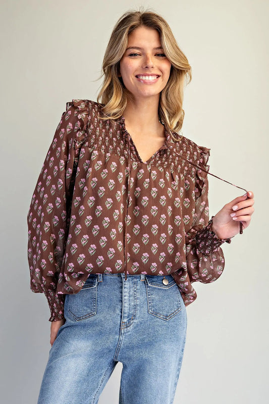 the Clara Floral Smocked Blouse featuring a micro floral print, V-neckline with tie detail, smocked yoke, ruffle shoulder trim, and long balloon sleeves