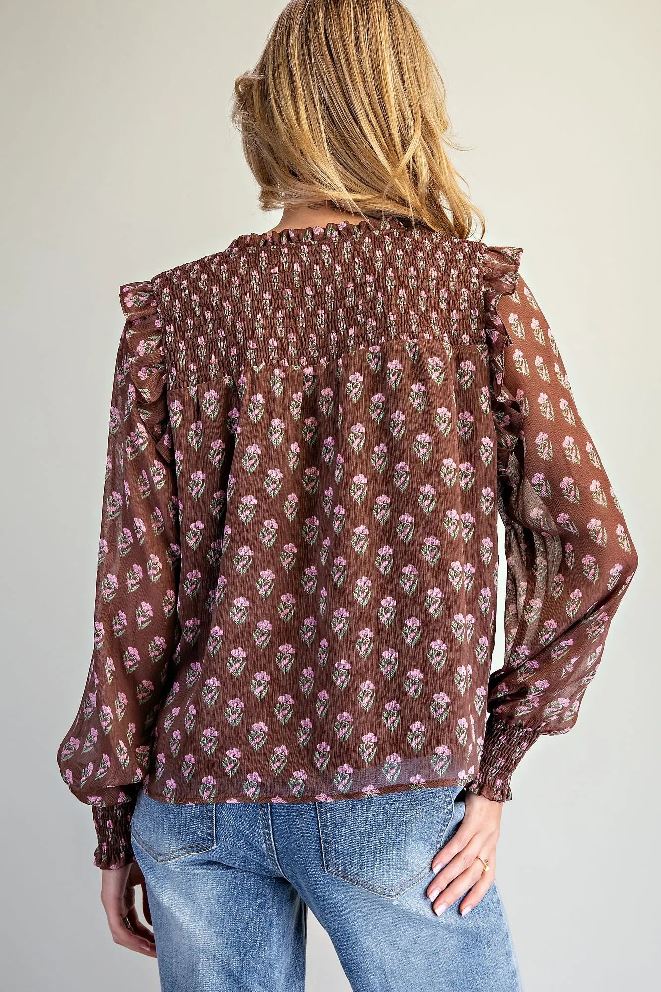 the Clara Floral Smocked Blouse featuring a micro floral print, V-neckline with tie detail, smocked yoke, ruffle shoulder trim, and long balloon sleeves