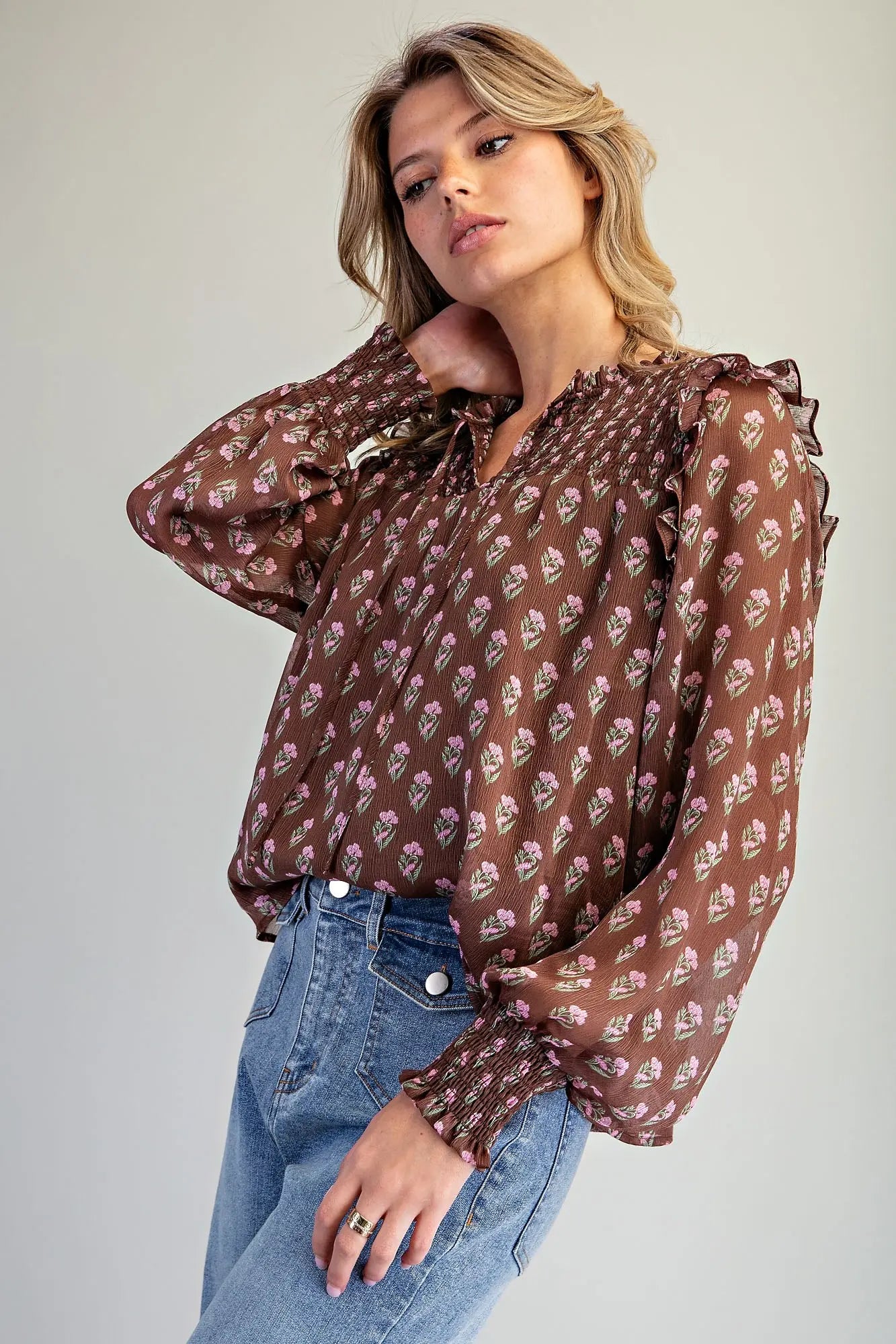 the Clara Floral Smocked Blouse featuring a micro floral print, V-neckline with tie detail, smocked yoke, ruffle shoulder trim, and long balloon sleeves