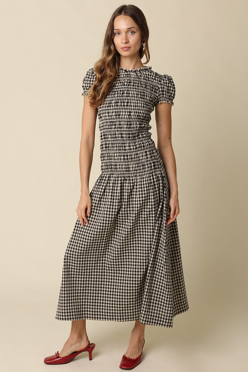 A romantic plaid maxi dress featuring soft puff sleeves, a fitted smocked bodice, and a flowing gathered skirt for an effortlessly feminine silhouette.