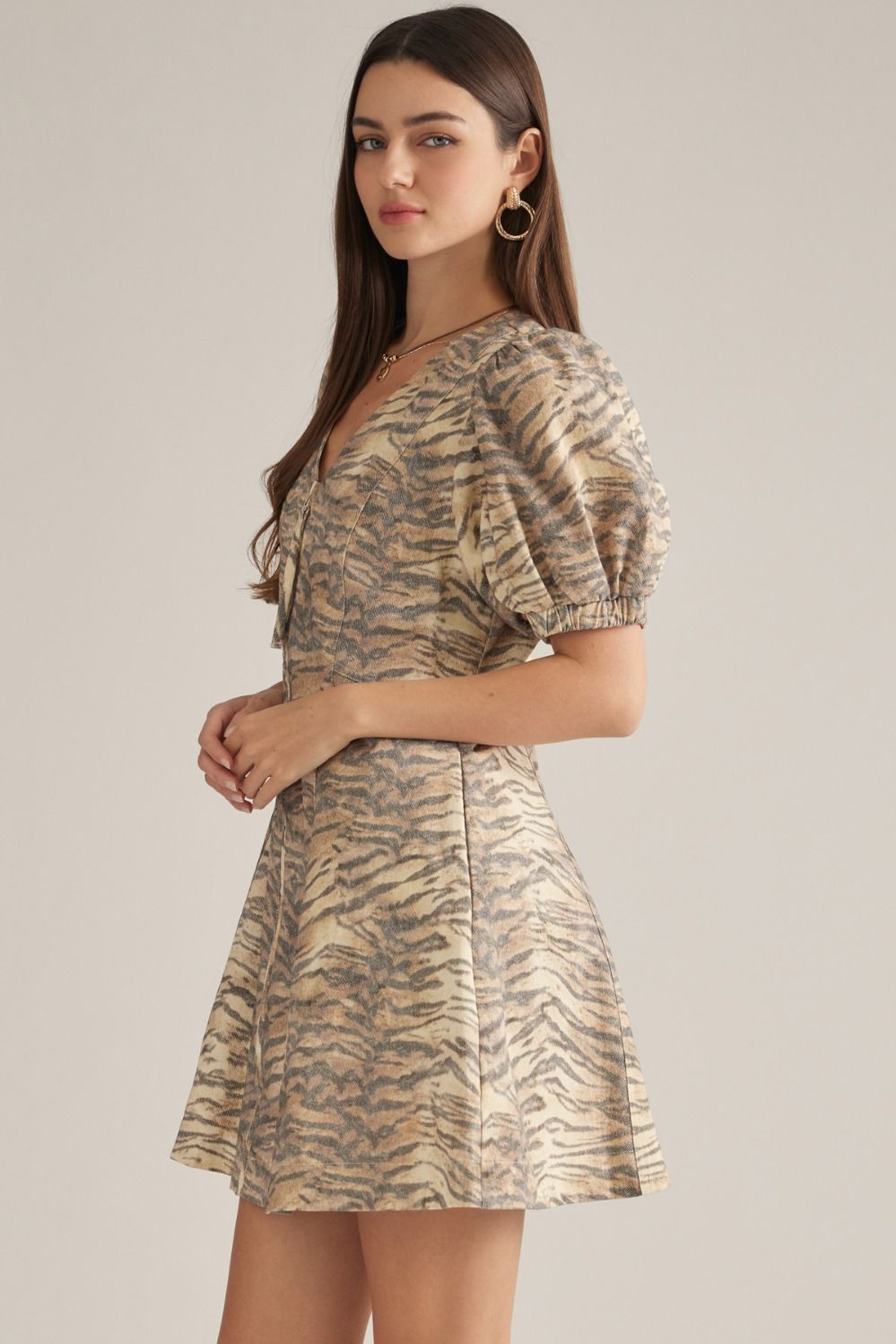 A playful cotton mini dress featuring a flattering V-neckline, short puff sleeves, and an easy front zipper closure in a chic animal print.

