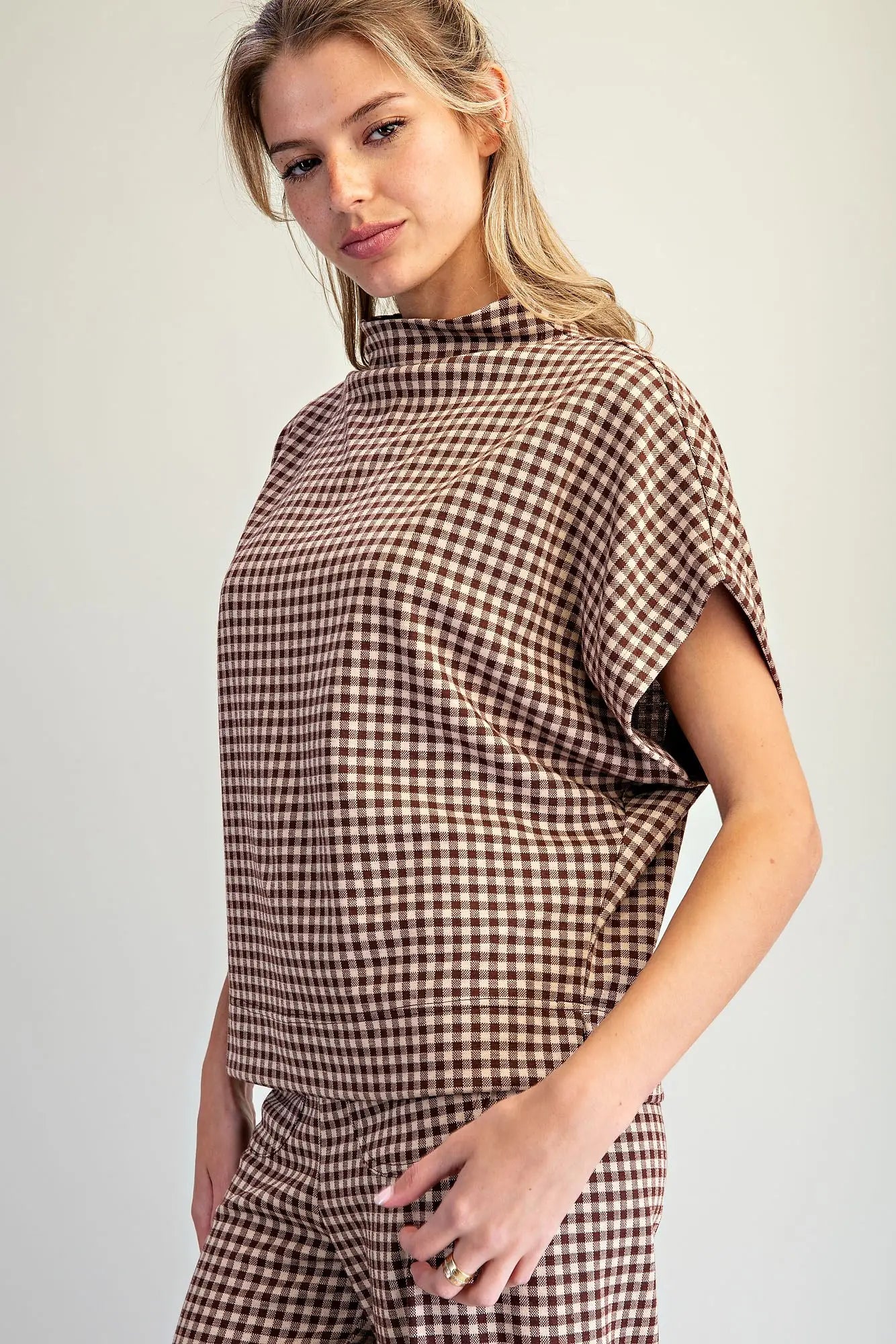 A relaxed gingham knit top featuring a modern mock neckline, wide dolman sleeves, and an effortlessly chic oversized silhouette.