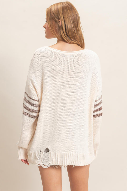 An effortlessly cool oversized knit sweater featuring a wide neckline, dropped shoulders, bold number detailing, and sporty sleeve stripes.
