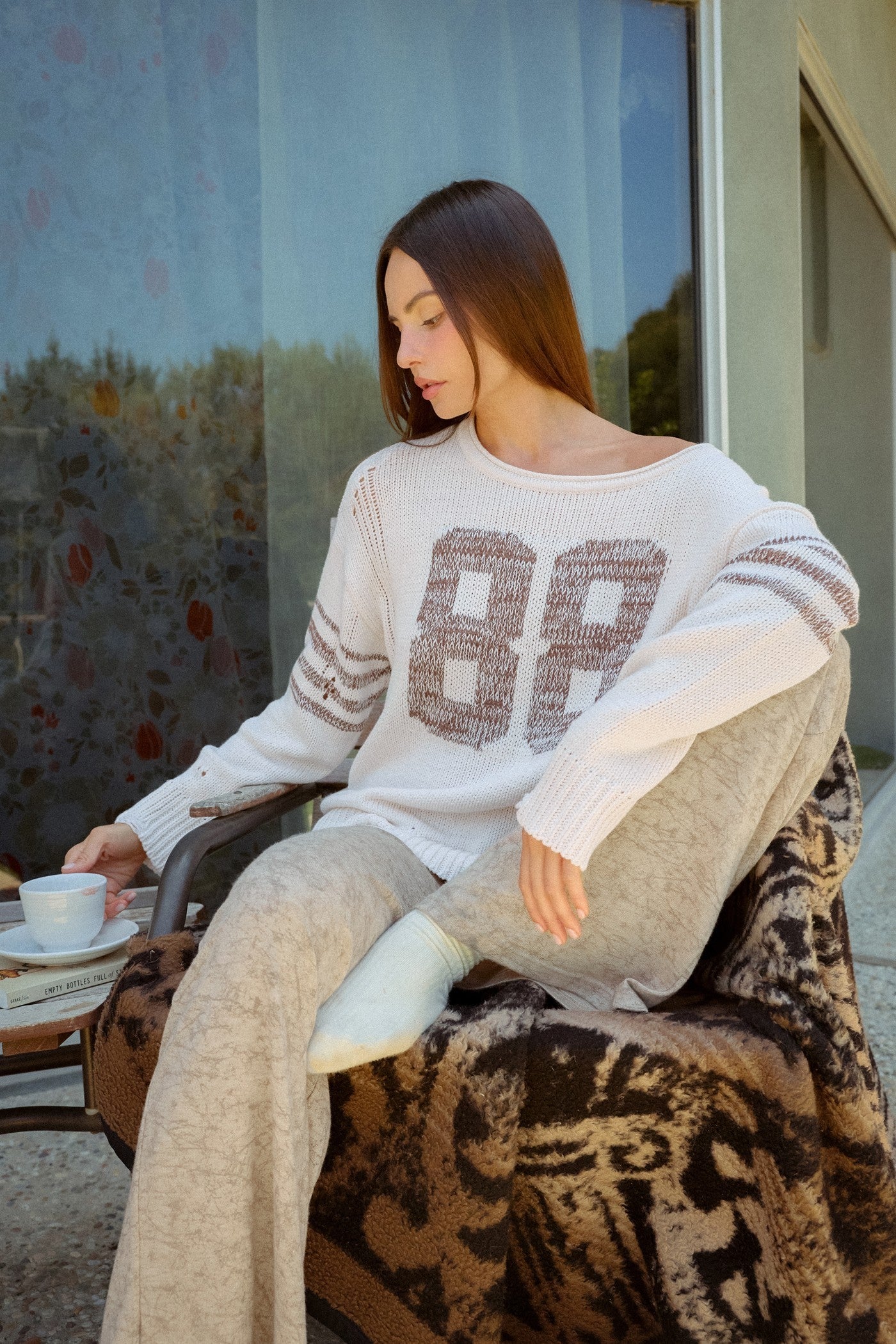 An effortlessly cool oversized knit sweater featuring a wide neckline, dropped shoulders, bold number detailing, and sporty sleeve stripes.
