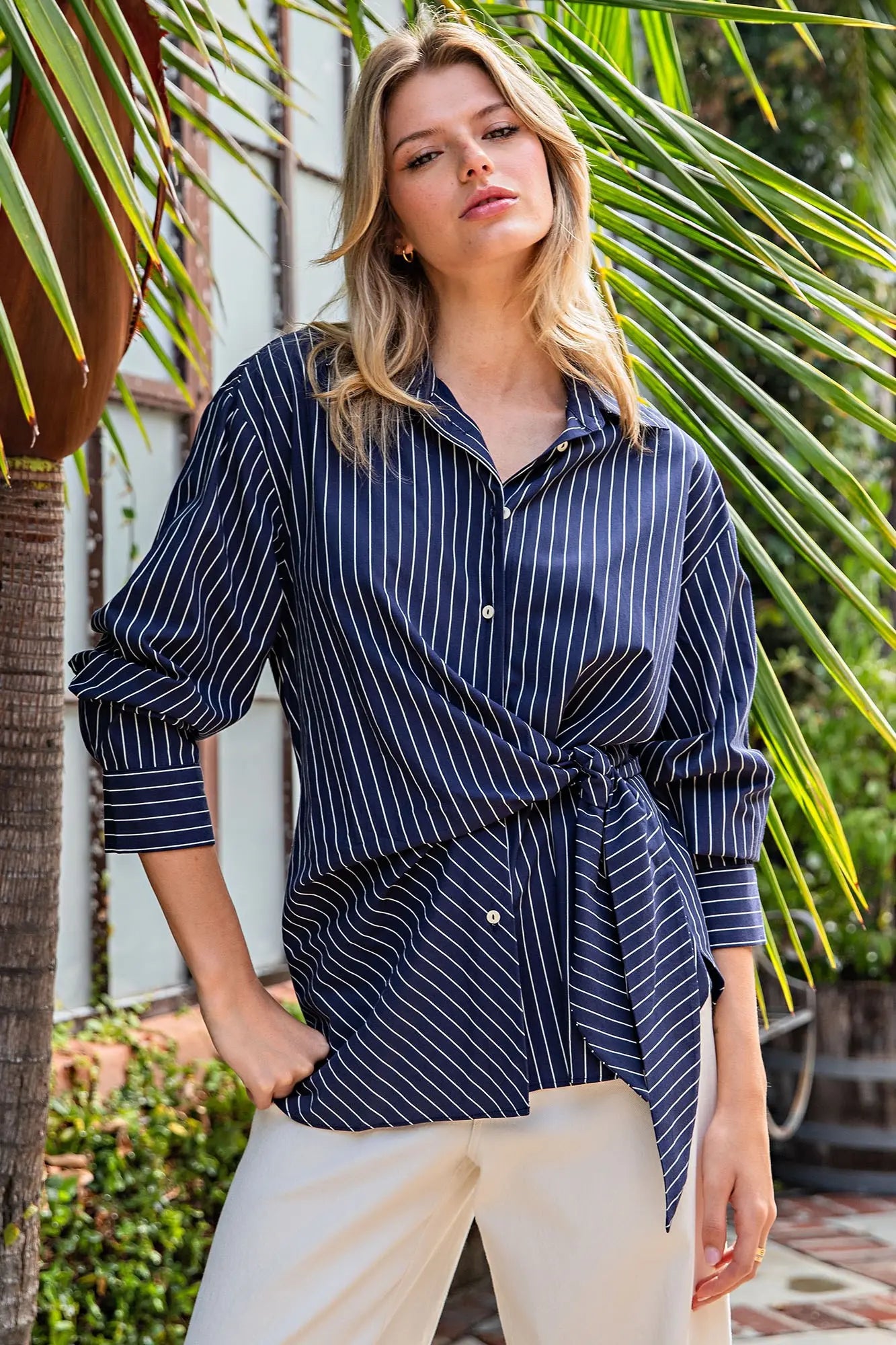 A chic pinstriped blouse featuring an asymmetric wrap-inspired silhouette, flattering hip tie, and classic button cuffs for a polished modern look.