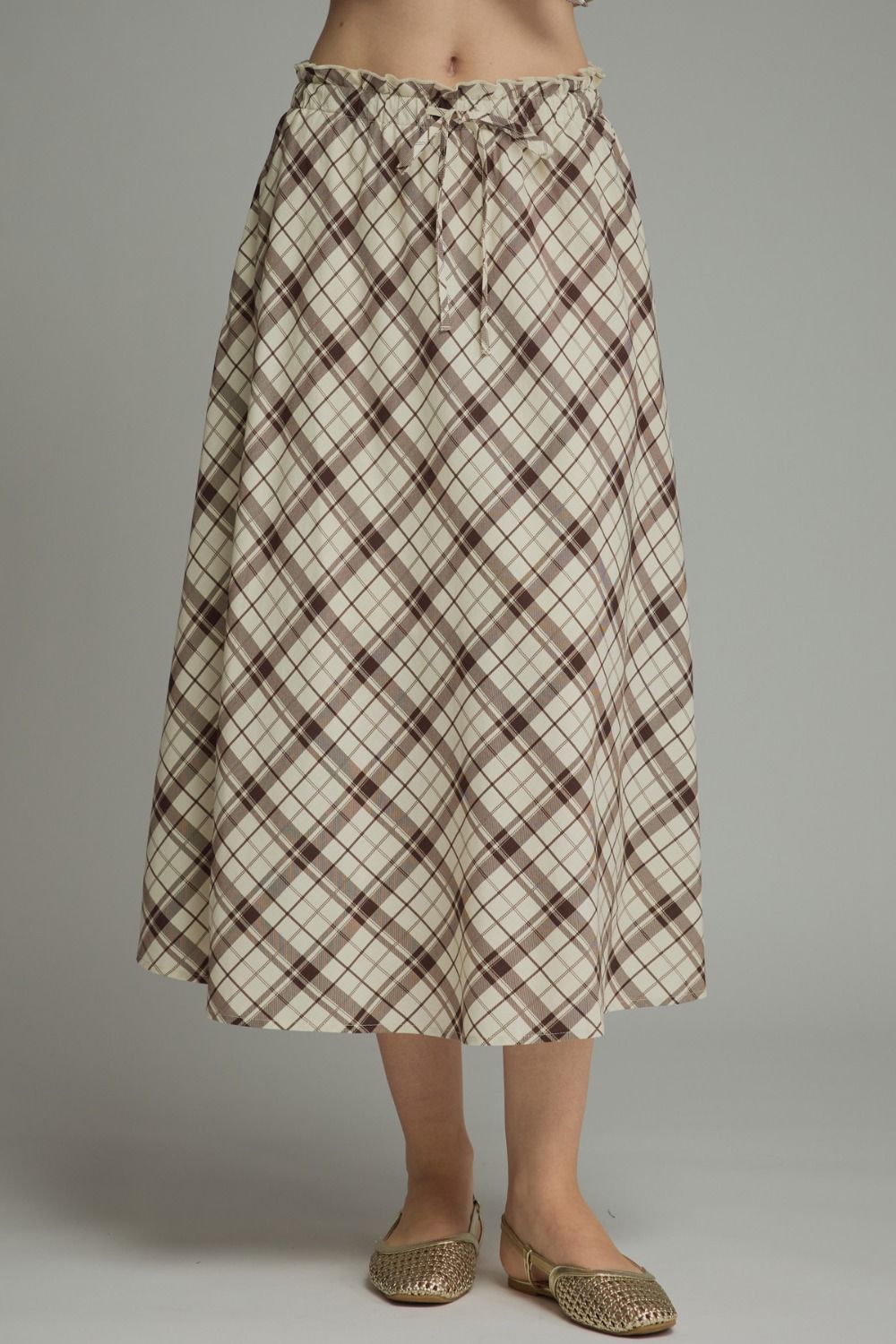 A breezy plaid midi skirt featuring a flattering self-tie waist and feminine ruffle detailing for effortless everyday elegance.

