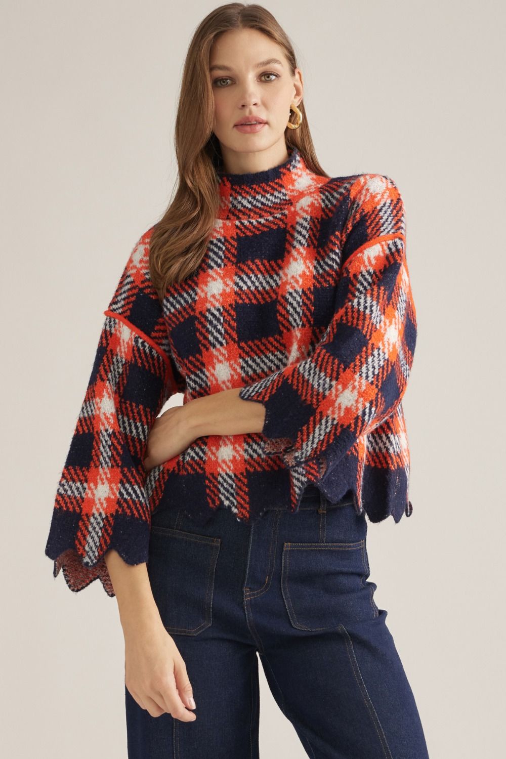 The Winifred Plaid Scalloped Hem Sweater Top brings classic plaid charm to a cozy knit silhouette finished with a feminine high neckline and scalloped hem.


