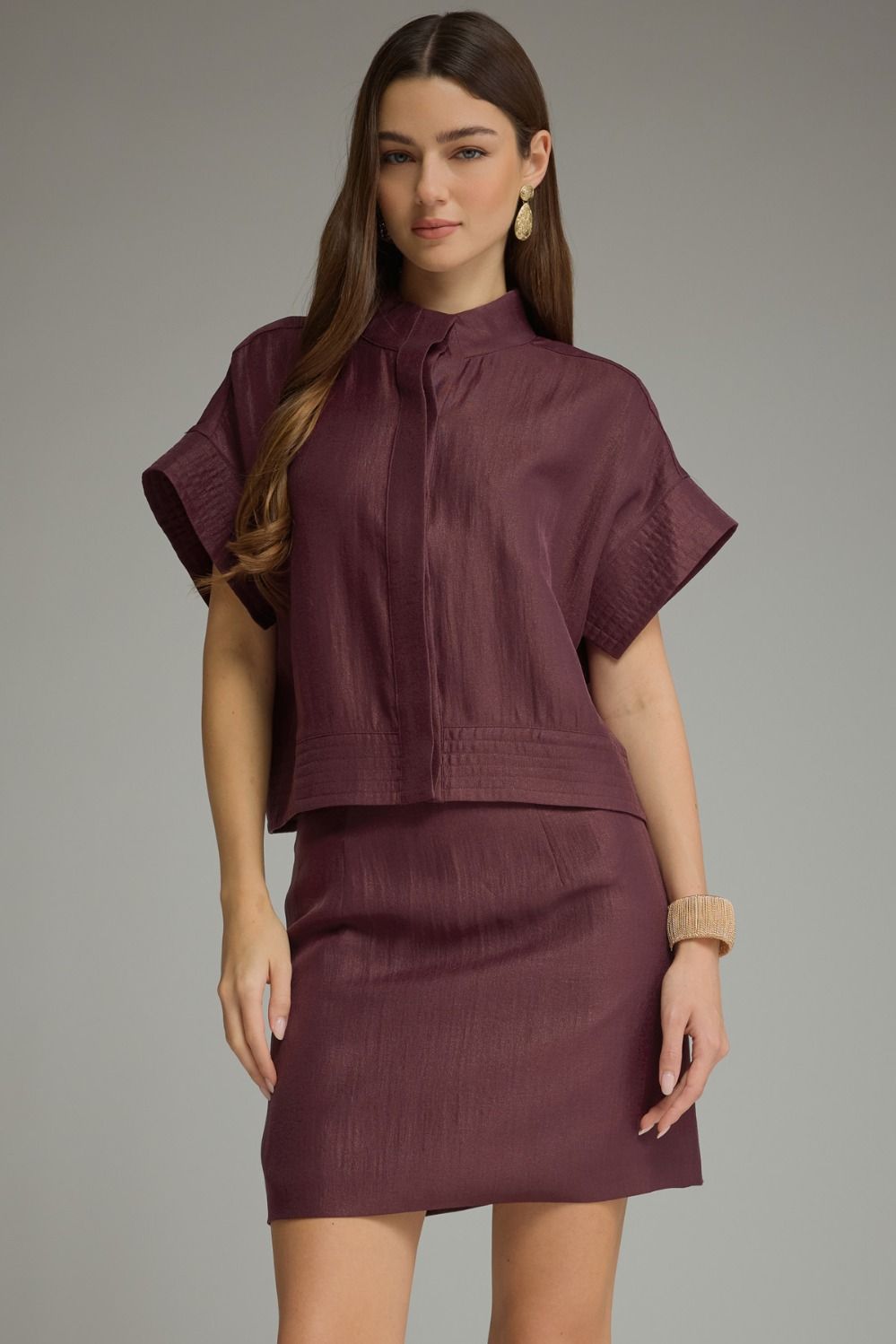 A polished two-piece set featuring a chic cropped top with wide cuffed sleeves paired with a sleek mini skirt for an effortlessly coordinated look.