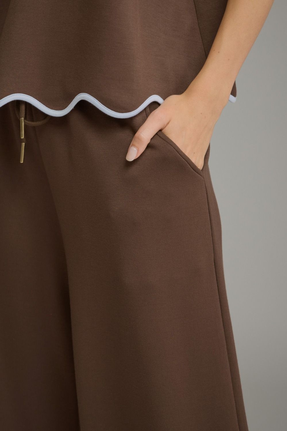 A polished two-piece knit set featuring a feminine scallop-trim top and coordinating drawstring pants for an effortlessly chic look from lounging to lunch.
