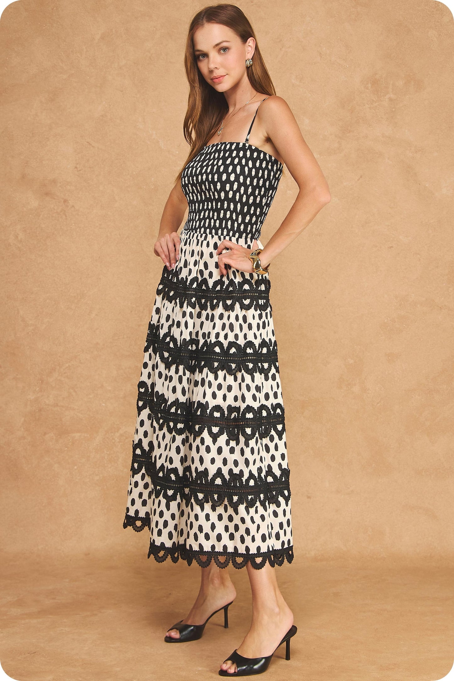 A stunning cotton midi dress featuring an abstract dot print, smocked bodice, adjustable straps, and crochet lace trim detailing for effortless bohemian elegance.