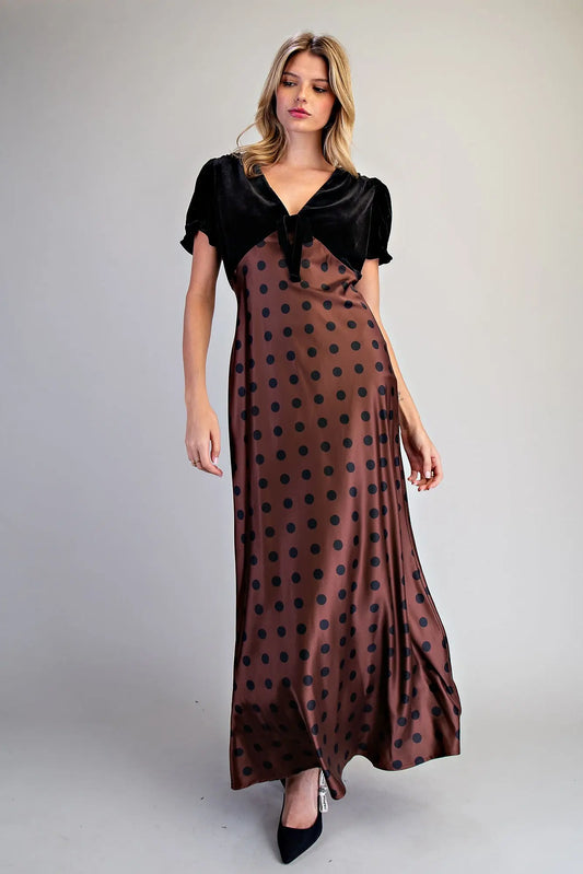 A romantic vintage-inspired maxi dress combining a velvet bodice, ruffled puff sleeves, bow neckline, and flowing satin polka dot skirt.