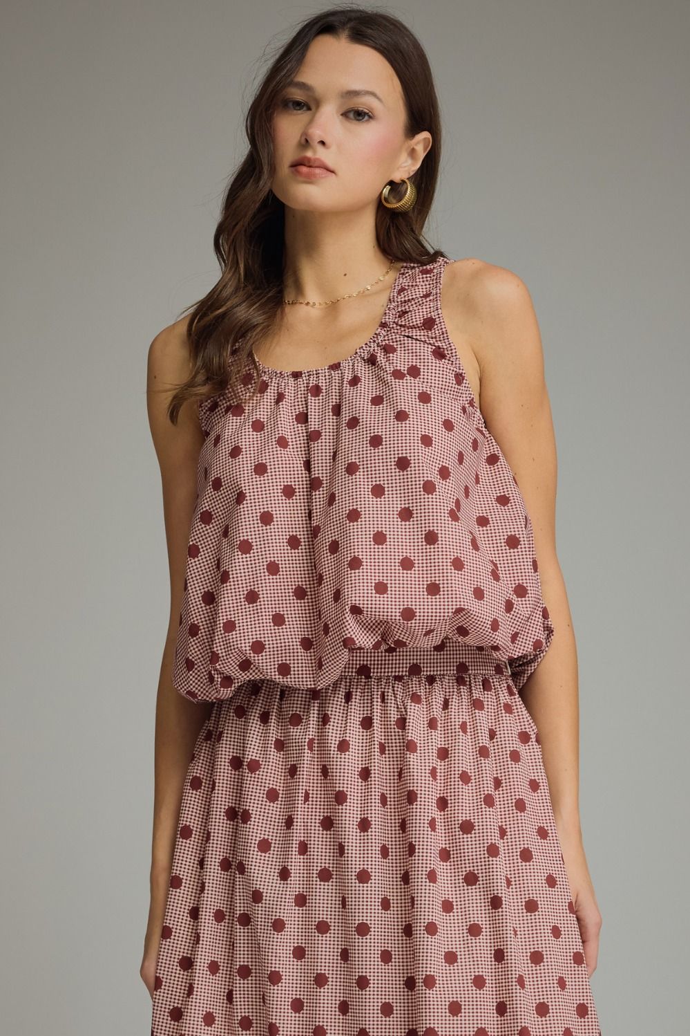 A charming gingham polka dot sleeveless top featuring a gathered neckline, elastic hem, and lightweight lined design for effortless feminine style.
