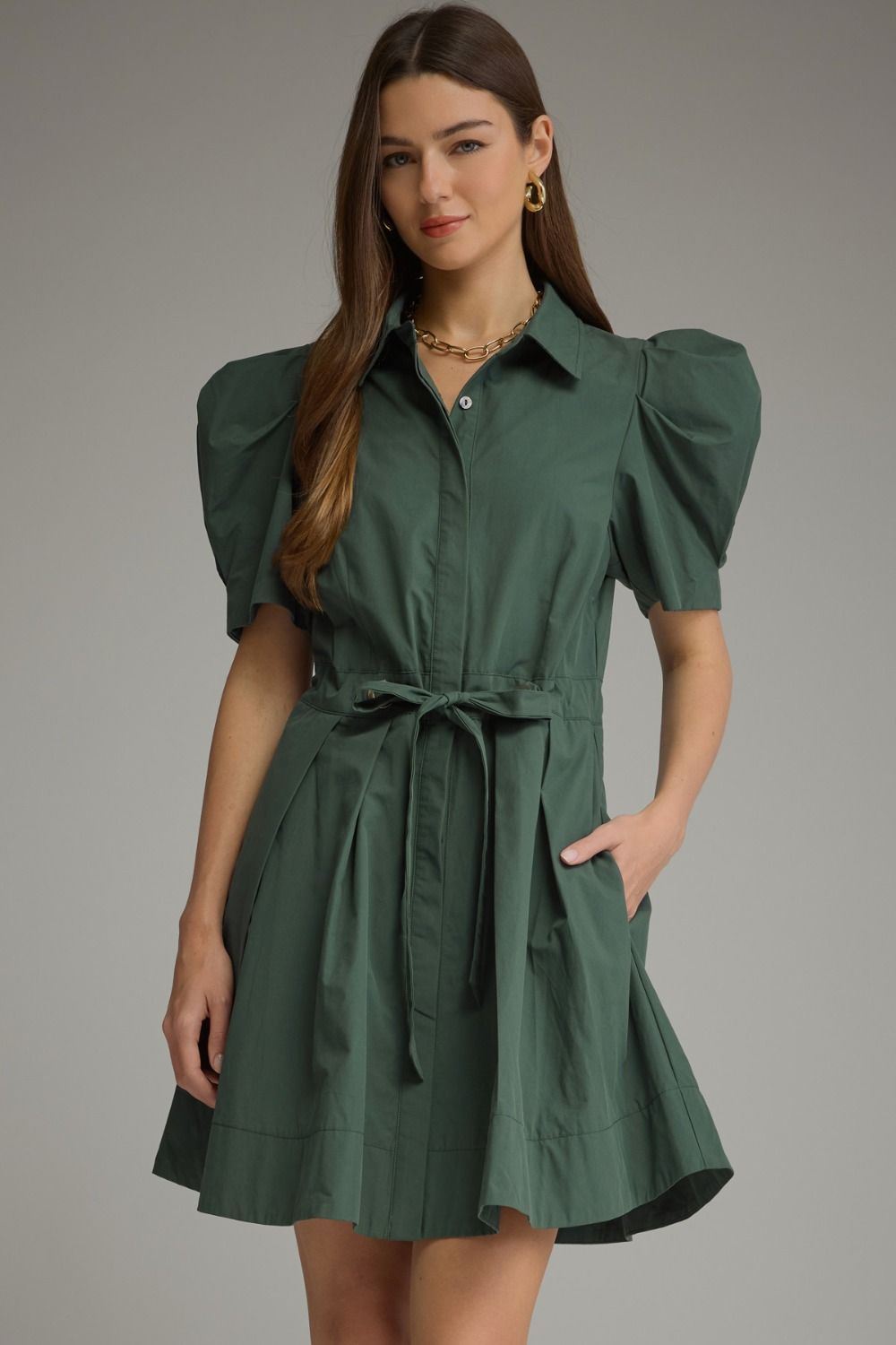 A feminine mini dress featuring playful puff sleeves, a classic shirt collar, waist tie detail, and a beautifully pleated skirt.

