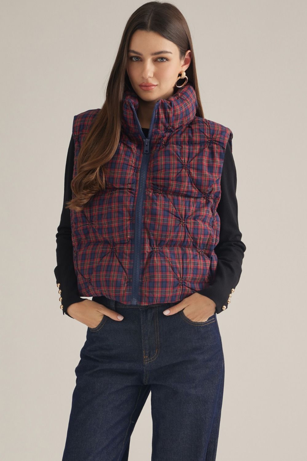 A cozy-chic plaid vest featuring a high neck, padded quilted construction, and a convenient front zipper for effortless layering through the cooler seasons.