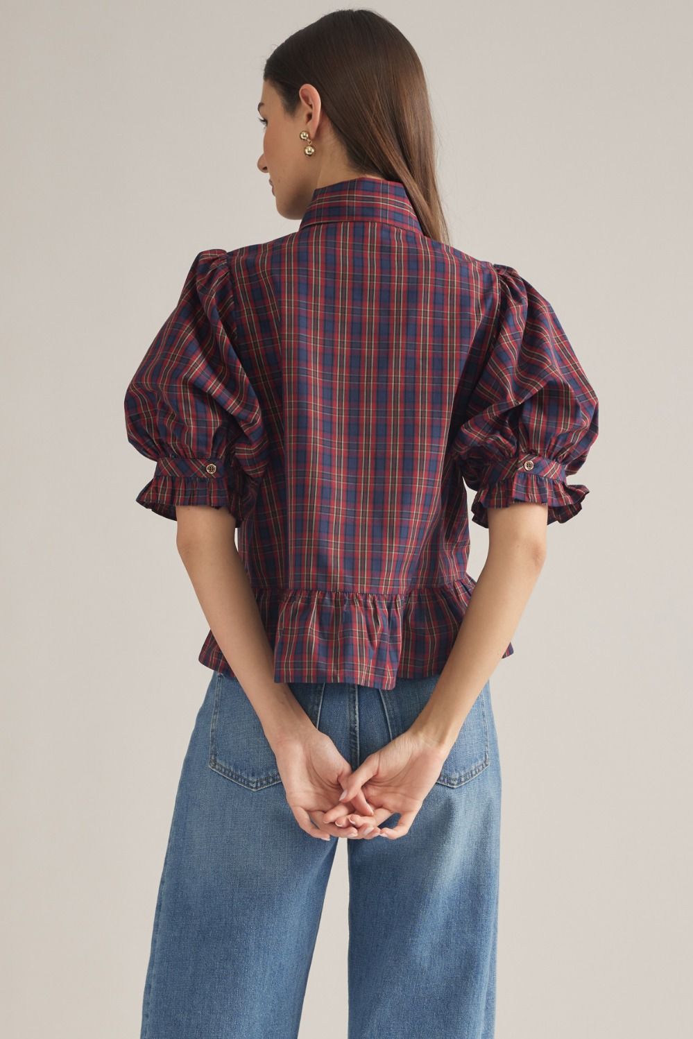 A charming plaid top featuring romantic puff sleeves, a coordinating scarf detail, ruffle hem, and classic button-front styling.