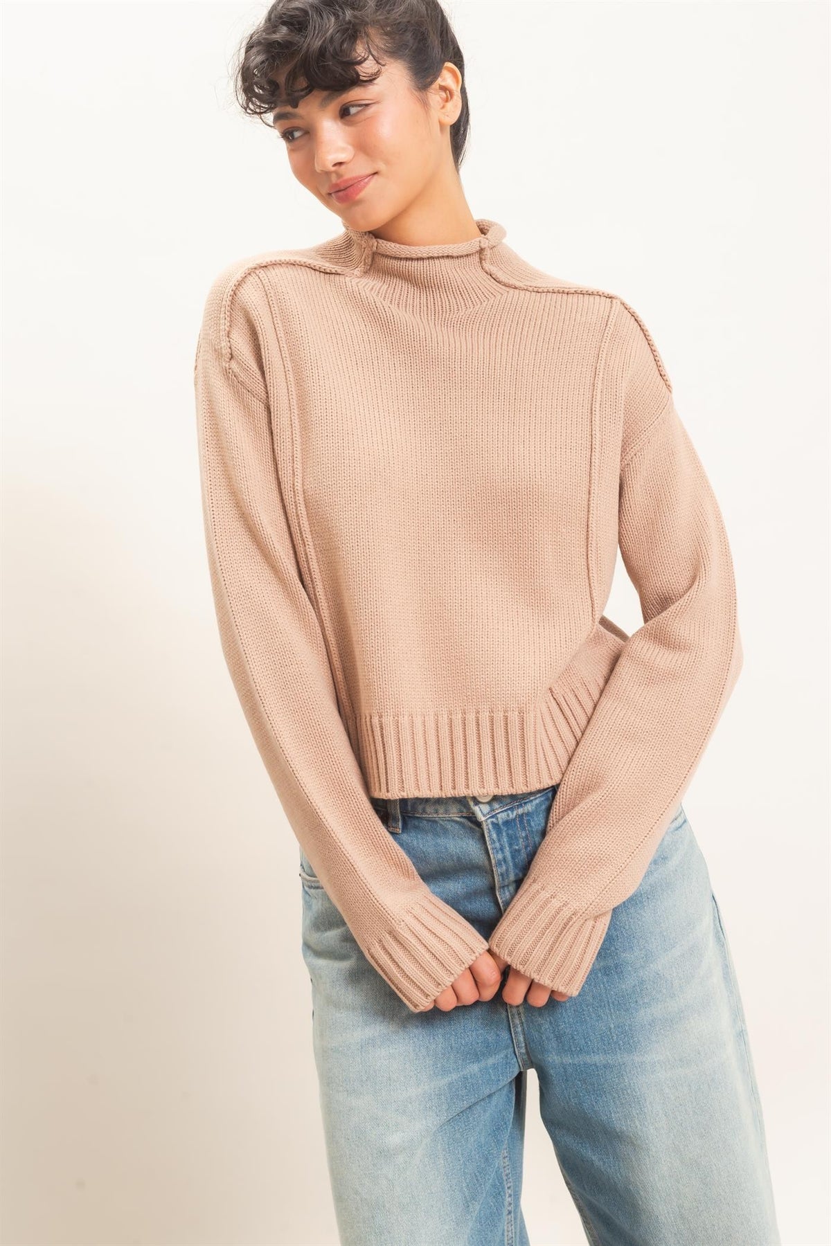 A cozy mid-weight roll neck sweater featuring distinctive reverse seam details, ribbed trim, and a relaxed silhouette for effortless everyday style.