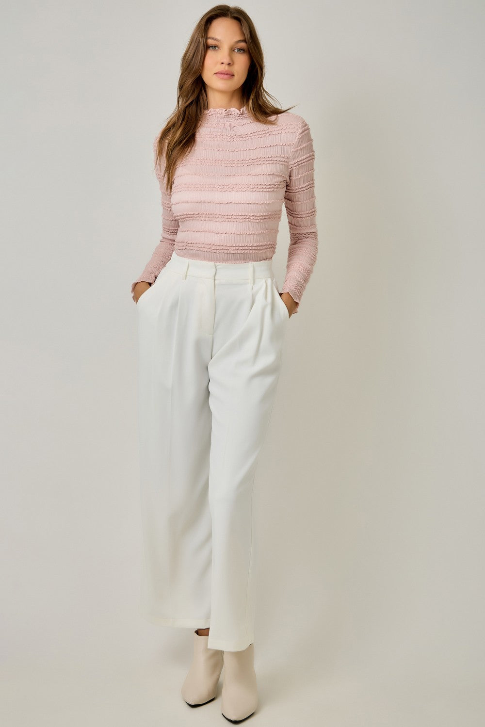 A feminine fitted knit top featuring a sleek mock neckline, long sleeves, and playful ruffled lettuce-edge stripes for a flattering statement look.

