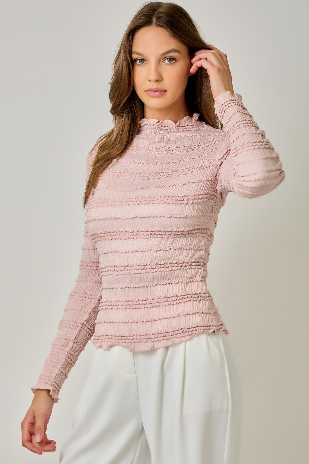 A feminine fitted knit top featuring a sleek mock neckline, long sleeves, and playful ruffled lettuce-edge stripes for a flattering statement look.
