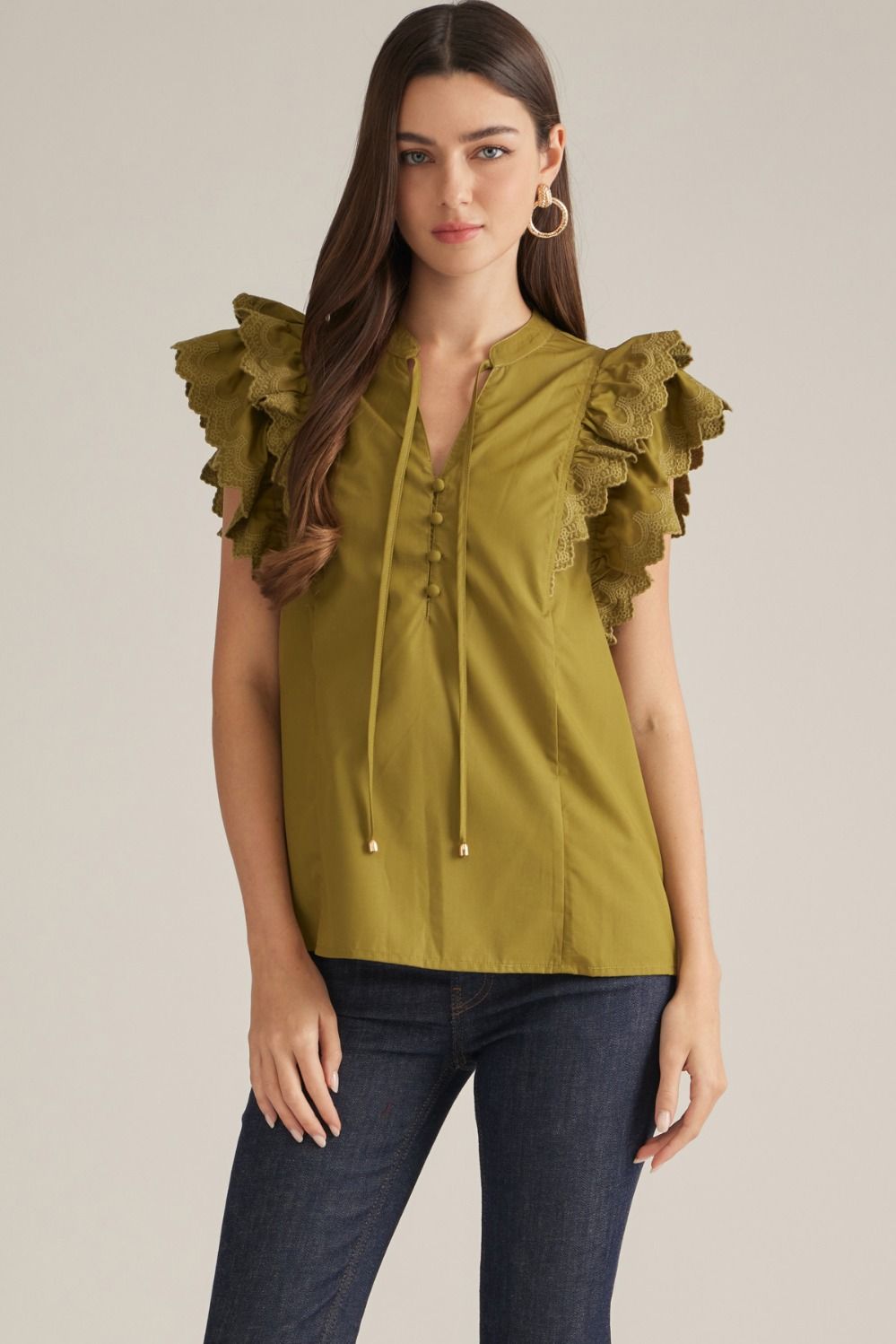 A feminine sleeveless top featuring a split neckline, front self-tie, and layered shoulder ruffles finished with delicate eyelet trim.
