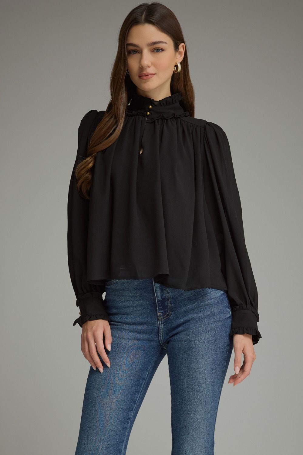 A romantic long sleeve blouse featuring a ruffled high neckline, gathered details, voluminous sleeves, and delicate ruffle-trimmed cuffs.

