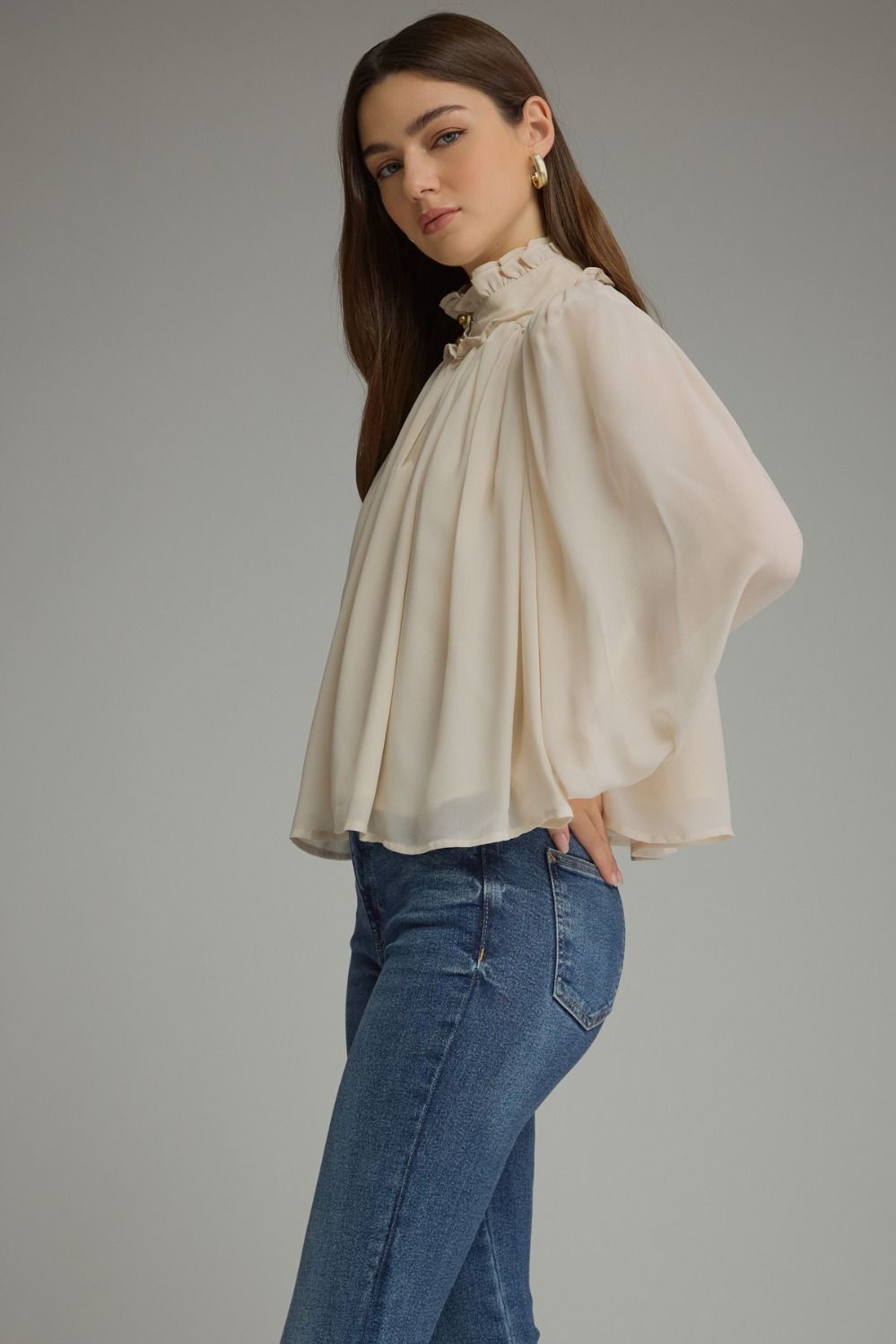 A romantic long sleeve blouse featuring a ruffled high neckline, gathered details, voluminous sleeves, and delicate ruffle-trimmed cuffs.

