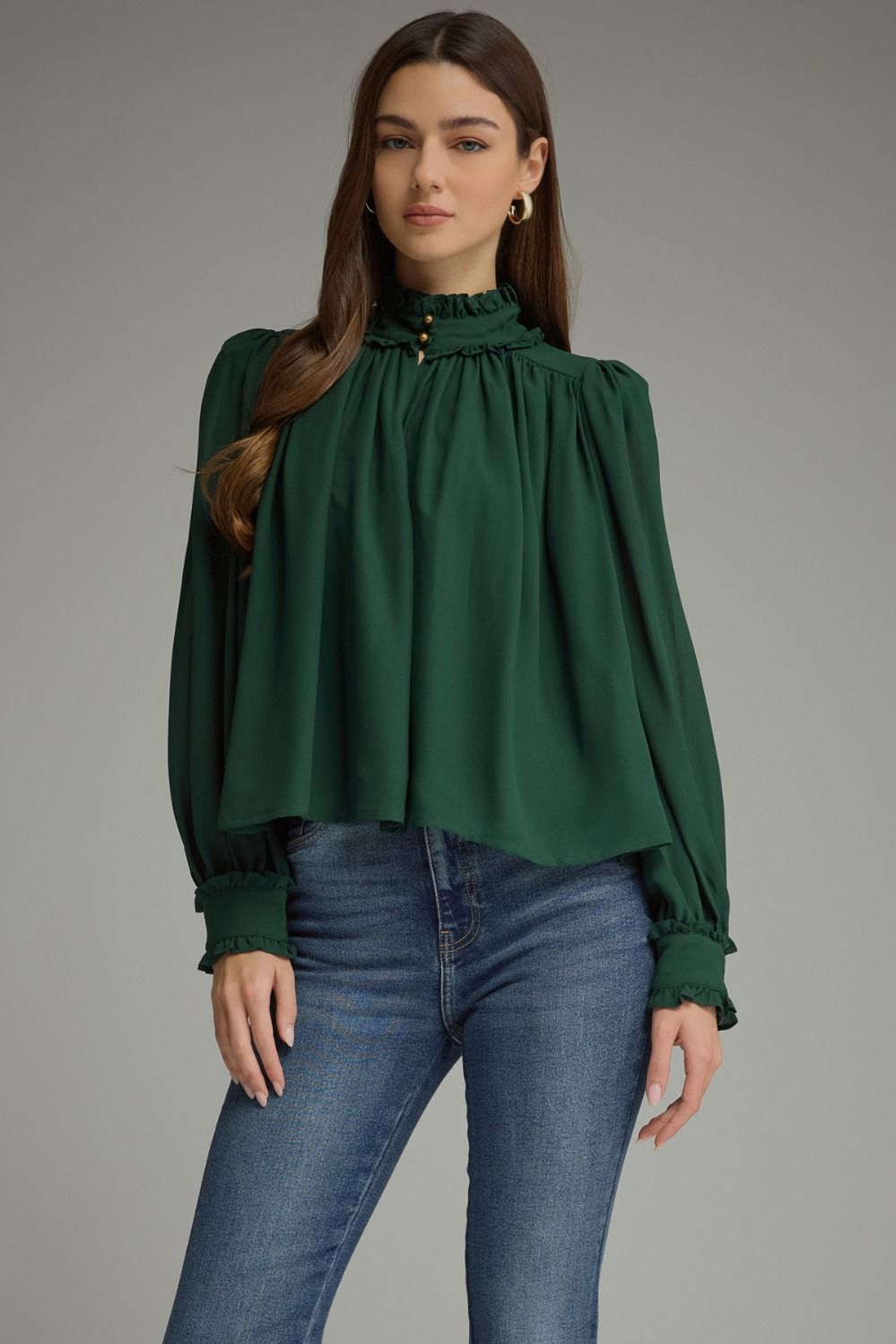 A romantic long sleeve blouse featuring a ruffled high neckline, gathered details, voluminous sleeves, and delicate ruffle-trimmed cuffs.

