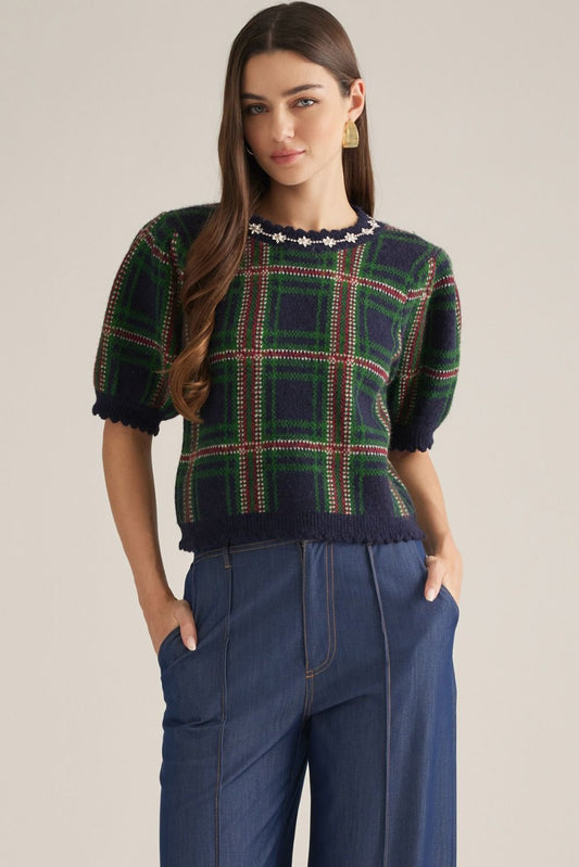 A charming plaid knit top featuring feminine puff sleeves, delicate embellished trim, and scalloped edges for a polished, vintage-inspired look.

